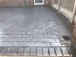 Pattern imprinted concrete driveway in Olde English Cobble with an acid stained edge