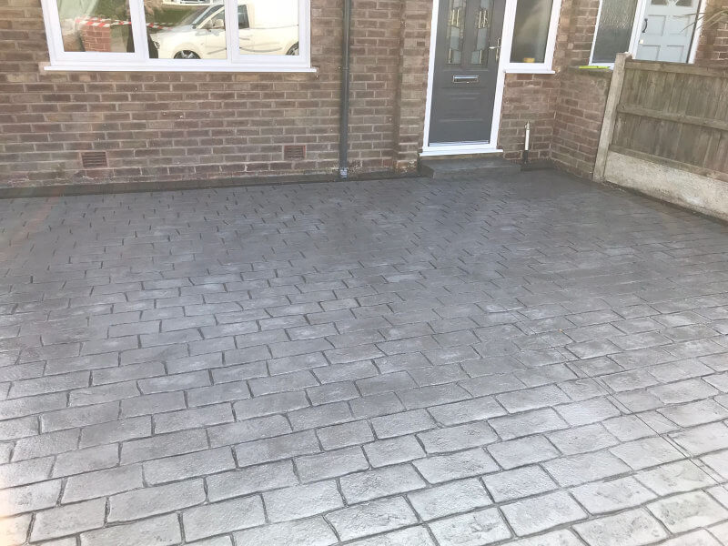 Pattern imprinted concrete driveway in Olde English Cobble with an acid stained edge