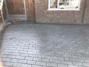 Pattern imprinted concrete driveway in Olde English Cobble with an acid stained edge