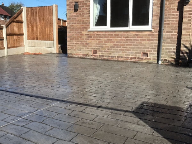 Pattern imprinted concrete driveway in Olde English Cobble with an acid stained edge